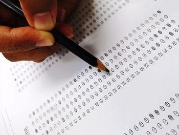 High angle view of hand holding pencil over paper