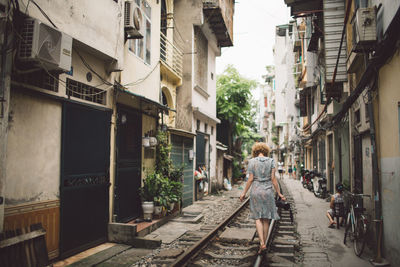 Woman walking on railroad track in city