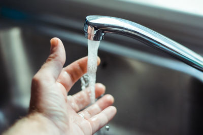 Cropped image of person washing hand in faucet
