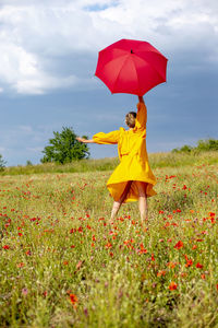 Woman with umbrella standing on field