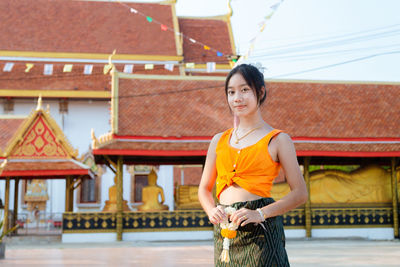 Young woman standing against building