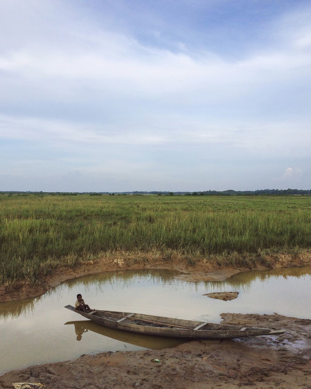 water, tranquil scene, tranquility, grass, sky, scenics, reflection, landscape, lake, standing water, calm, beauty in nature, horizon over land, cloud, nature, field, non-urban scene, cloud - sky, day, green color, marsh, outdoors, waterfront, solitude, rural scene, no people, green, cloudy, countryside, majestic