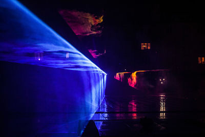 Reflection of illuminated boat in sea at night