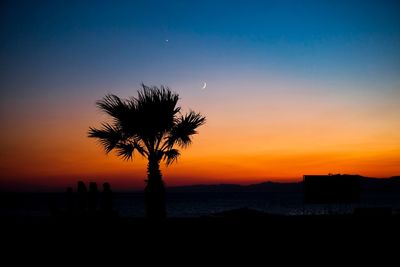 Silhouette palm trees on beach against sky during sunset