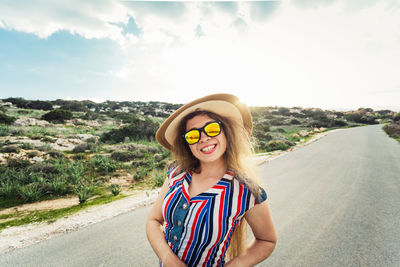 Portrait of young woman standing against sky