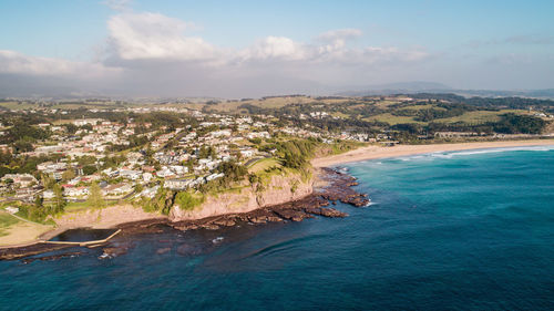 Aerial view of townscape by sea against sky