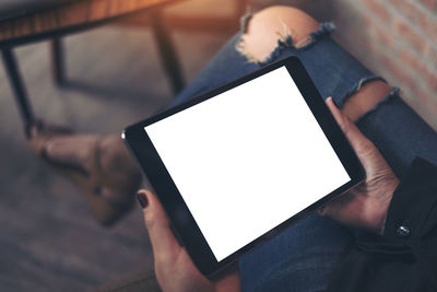 Low section of woman holding digital tablet