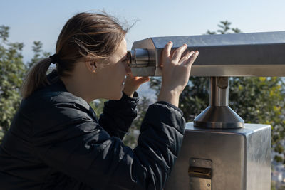 Side view of woman photographing through binoculars