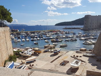 Sailboats moored in sea by city against sky