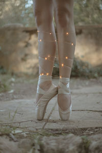 Low section of ballet dancer wearing illuminated lights standing outdoors