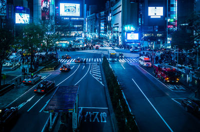 High angle view of illuminated street amidst buildings in city at night