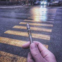 Human hand holding umbrella on road