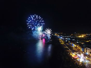 Low angle view of firework display over river against sky