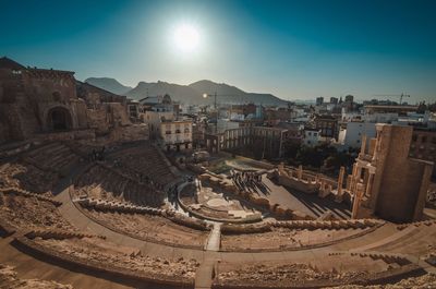 Roman theatre by buildings against sky