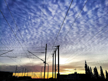 Low angle view of silhouette electricity pylon against sky