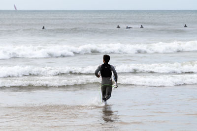 Rear view of man with surfboard at beach