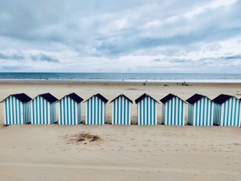 Scenic view of beach huts in a row on beach against sky