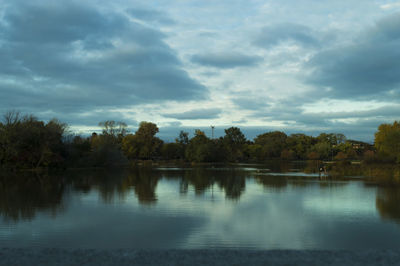 Reflection of trees in lake against cloudy sky
