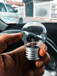 Cropped hand holding light bulb in car