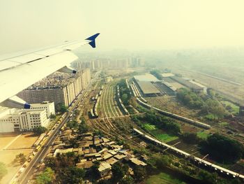 Aerial view of airplane wing over cityscape against sky