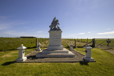 Cross in cemetery against sky