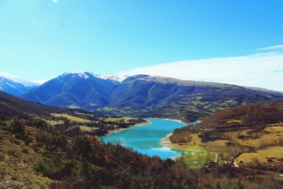 Scenic view of lake and mountains against blue sky