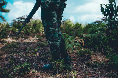 Low section of soldier standing by plants