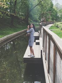 Side view of man holding umbrella on bridge