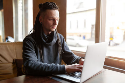 Mid adult man using mobile phone while sitting on table