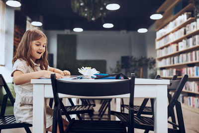 Schoolgirl doing puzzle and reading book in school library. primary school pupil is engaged in book