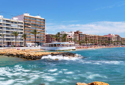 Buildings by sea against sky in city