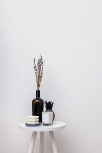 Vase and candles on small table over the white wall, minimalist home decor