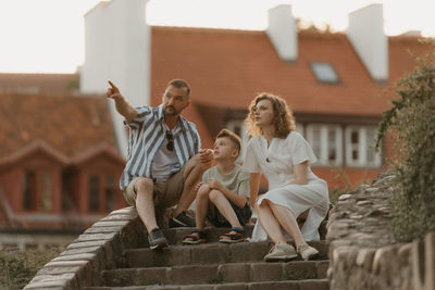 Side view of woman sitting on retaining wall