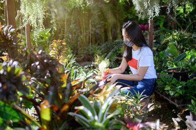Side view of woman sitting on plant