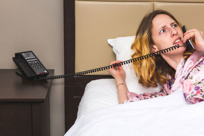 Midsection of woman using mobile phone on bed at home