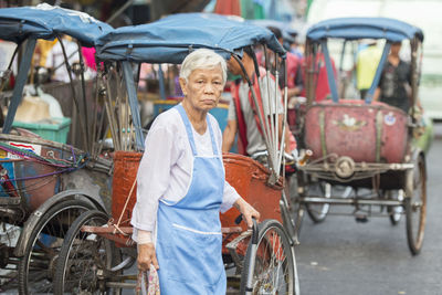 Senior woman standing by jinrikishas on road