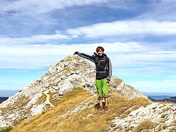 Woman standing on cliff against the sky