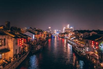 Canal amidst illuminated buildings in city at night