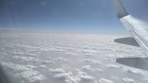 Aerial view of aircraft wing over landscape against sky