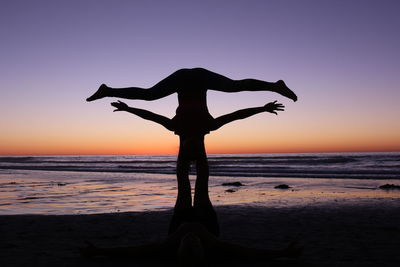 Silhouette couple at beach against clear sky during sunset