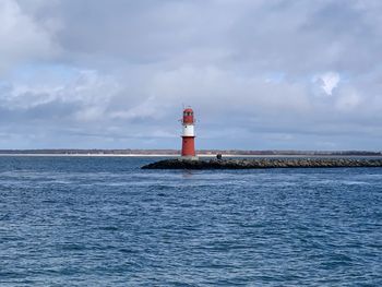 Lighthouse by sea against sky