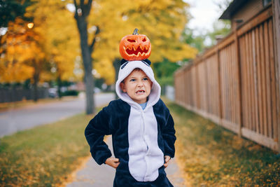 Cute boy with pumpkin standing outdoors