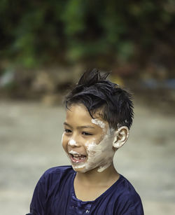 Smiling boy with messy face looking away outdoors