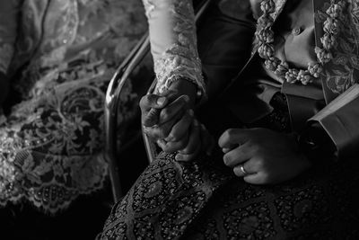 Midsection of bride holding groom hand during wedding ceremony