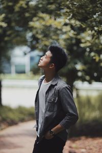 Young man looking away while standing at park