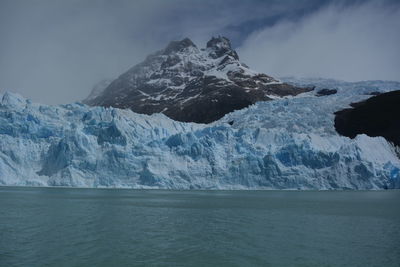 Scenic view of sea and snowcapped mountains against sky