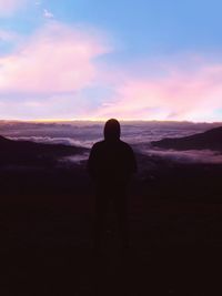 Rear view of silhouette man looking at sunset