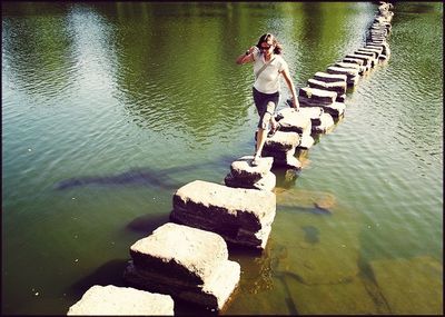 Full length of man standing on rock by lake