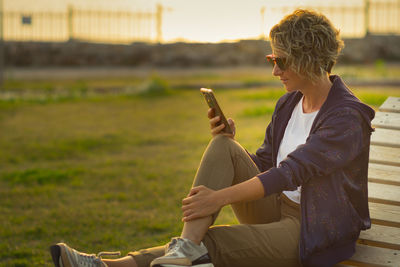 Side view of young man sitting on field