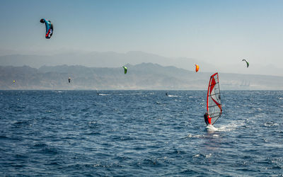 Man paragliding over sea against clear sky